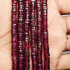 May include: Multiple strands of faceted, deep red gemstone beads. The beads are small, with a geometric cut that catches the light, creating a sparkling effect. The beads are strung together. The overall colour is a rich, dark red.