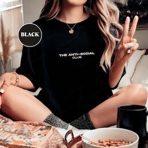 K&ouml;nnte beinhalten: Schwarzes T-Shirt mit Rundhalsausschnitt und dem wei&szlig;en Text "THE ANTI-SOCIAL CLUB". Das Shirt hat eine schwarze Farbe. Ein schwarzer Kreis mit dem Wort "BLACK" befindet sich in der oberen linken Ecke des Bildes.