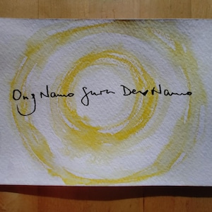 Könnte beinhalten: Aquarellmalerei auf Papier mit einem gelben Spiraldesign und schwarzem handschriftlichem Text. Der Text lautet "Ong Namo Guru Dev Namo". Das Kunstwerk befindet sich auf einem weißen rechteckigen Papier.