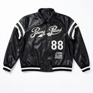 Peut inclure: Veste en cuir noire avec des détails blancs et le texte "Strong Island" en écriture manuscrite. La veste présente des rayures blanches sur les manches et le numéro "88". Un écusson "Strong Island Long Island" est également visible.