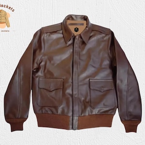 May include: A brown leather jacket with a collared neckline, two front pockets, and a ribbed hem and cuffs. The jacket has a zipper closure and is labeled "Kraft Jackets Leather Jackets" in a circular logo.
