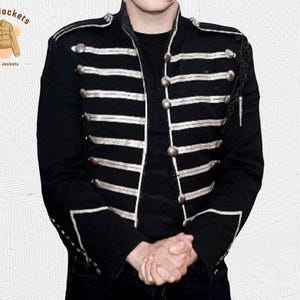 May include: Black jacket with silver-colored horizontal stripes and buttons. The jacket has a military-style design with decorative fringe on the shoulders. The brand logo "Kraft Jackets Leather Jackets" is in the upper left corner.