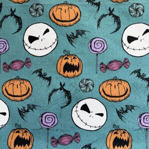 Puede incluir: Tela color turquesa con un patr&oacute;n repetido de calabazas naranjas, caras blancas de Jack Skellington, murci&eacute;lagos negros, piruletas moradas y caramelos envueltos. El dise&ntilde;o tiene un tema de Halloween.