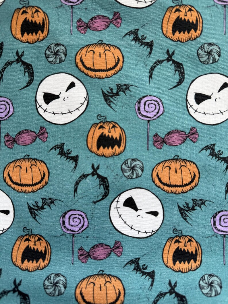 Puede incluir: Tela color turquesa con un patr&oacute;n repetido de calabazas naranjas, caras blancas de Jack Skellington, murci&eacute;lagos negros, piruletas moradas y caramelos envueltos. El dise&ntilde;o tiene un tema de Halloween.