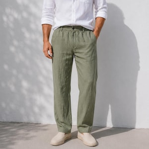 Op de afbeelding: Olijfgroene linnen broek met een relaxte pasvorm. De broek heeft een knoopsluiting en zakken. Het model draagt de broek met een wit overhemd en beige instappers.