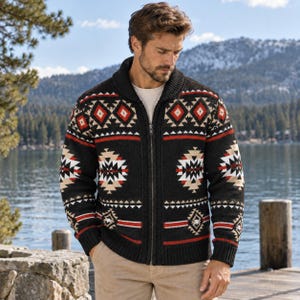 Op de afbeelding: Een zwart vest met rits, sjaalkraag en een geometrisch patroon in rood, wit en beige. De gebreide trui heeft lange mouwen met geribbelde boorden en een geribbelde zoom, met een herhalend ruit- en chevronmotief over de borst.