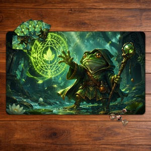 Pode incluir: Um tapete de jogo retangular com uma ilustração de fantasia de um sapo mago com capa e capuz, segurando um cajado brilhante. O sapo conjura um símbolo de folha mágica verde vibrante. Inclui um pequeno baralho de cartas e vários dados.