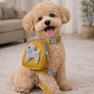 May include: A light brown poodle wearing a yellow backpack harness with a gray dog applique and a blue bow tie. The dog also has a matching yellow collar and leash. The dog is sitting on a light-colored carpet.