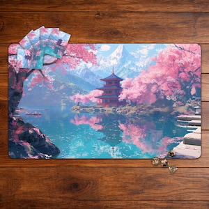 May include: A playmat featuring a serene Japanese landscape with a pagoda, cherry blossoms, and a lake reflecting the scene. The mat has a blue and pink color scheme with a mountain backdrop. Several game cards and dice are visible.