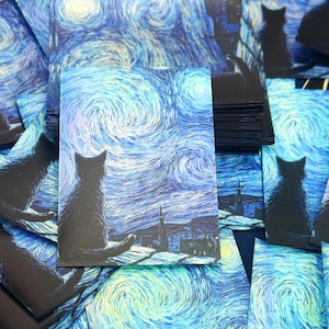 May include: A stack of rectangular postcards featuring a dark silhouette of a cat sitting on a roof, overlooking a swirling blue and yellow night sky inspired by Van Gogh's Starry Night. The artwork displays thick, textured brushstrokes.