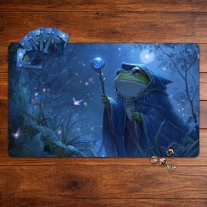 May include: A fantasy-themed playmat featuring a green frog wizard in a blue robe, holding a staff with a glowing blue orb. The background depicts a moonlit forest with glowing fireflies. Includes matching cards and dice.
