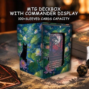 Op de afbeelding: Een rechthoekige MTG-deckbox met een displayvenster voor een commander, voorzien van een print van een zwarte kat tussen groene leliebladeren en roze lotusbloemen. De tekst luidt MTG DECKBOX WITH COMMANDER DISPLAY en 100+ SLEEVED CARDS CAPACITY.