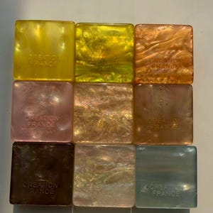 May include: Nine square-shaped decorative items in various colors, including yellow, gold, orange, pink, brown, and green. Each item has a pearlescent finish and the text "CREATION FRANCE" printed on it.