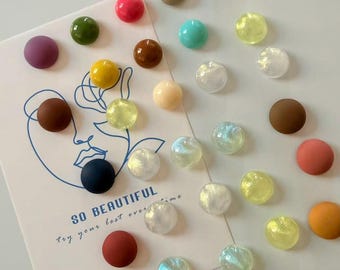 May include: An assortment of colorful, round decorative beads in various colors, including pink, green, yellow, and iridescent. Some beads are opaque, while others are translucent. A card with the text "SO BEAUTIFUL" is also present.