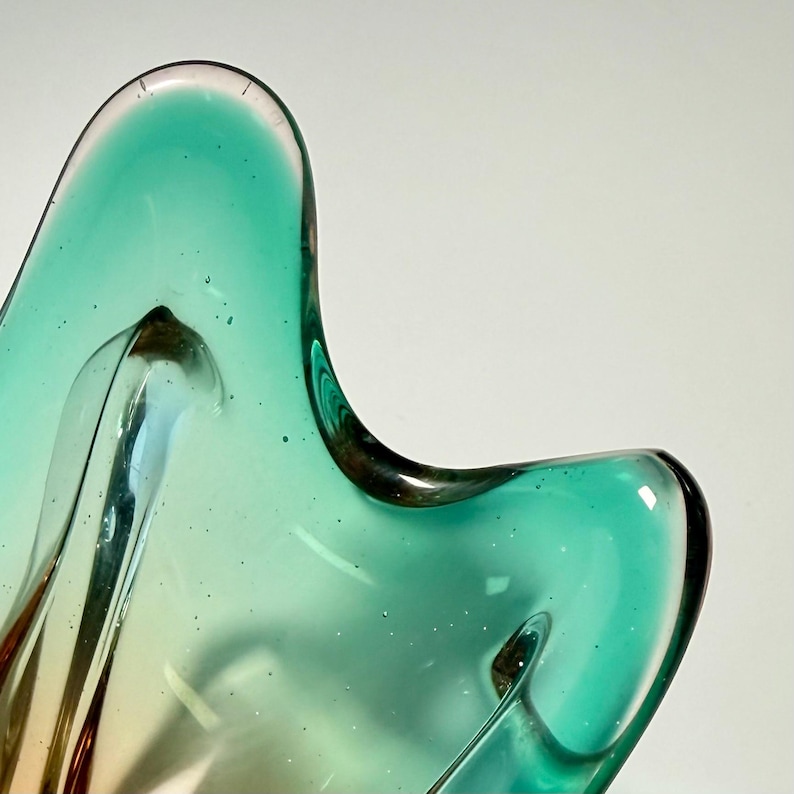 Vintage Czech art glass bowl in green and amber tones with sculptural organic shape and dramatic light reflections.