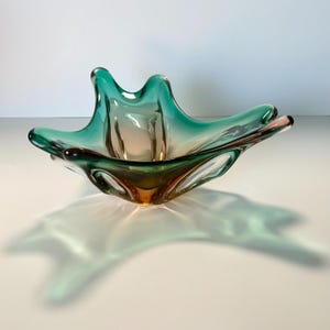Vintage Czech art glass bowl in green and amber tones with sculptural organic shape and dramatic light reflections.