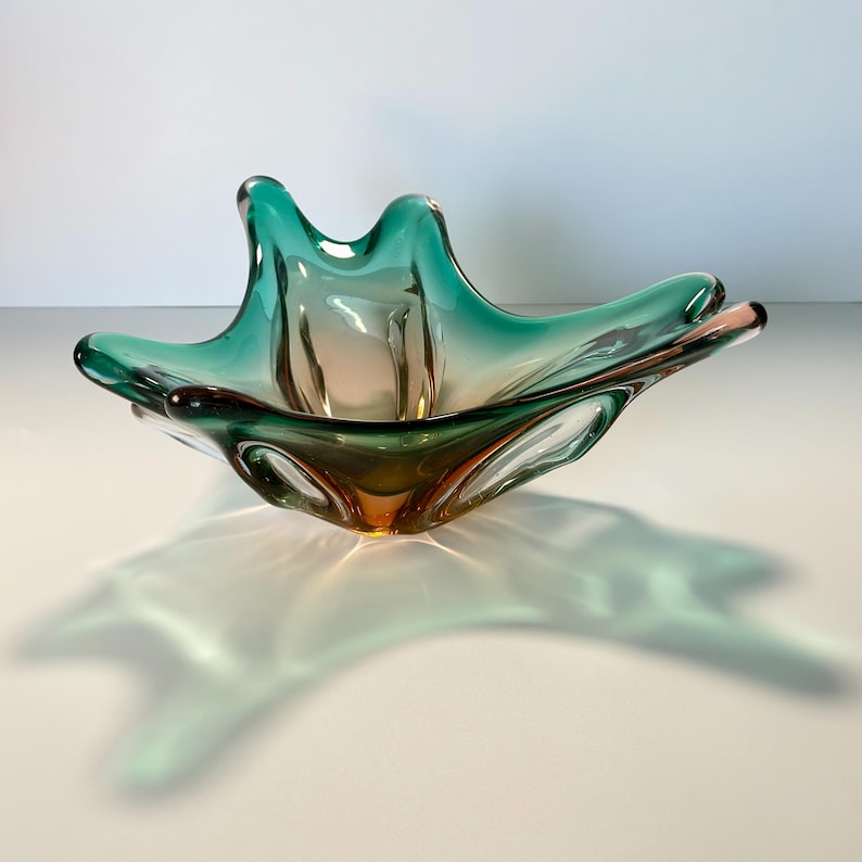Vintage Czech art glass bowl in green and amber tones with sculptural organic shape and dramatic light reflections.