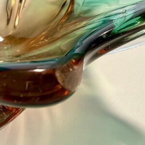 Vintage Czech art glass bowl in green and amber tones with sculptural organic shape and dramatic light reflections.