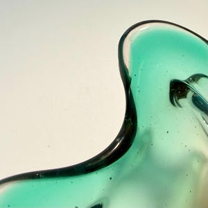 Vintage Czech art glass bowl in green and amber tones with sculptural organic shape and dramatic light reflections.