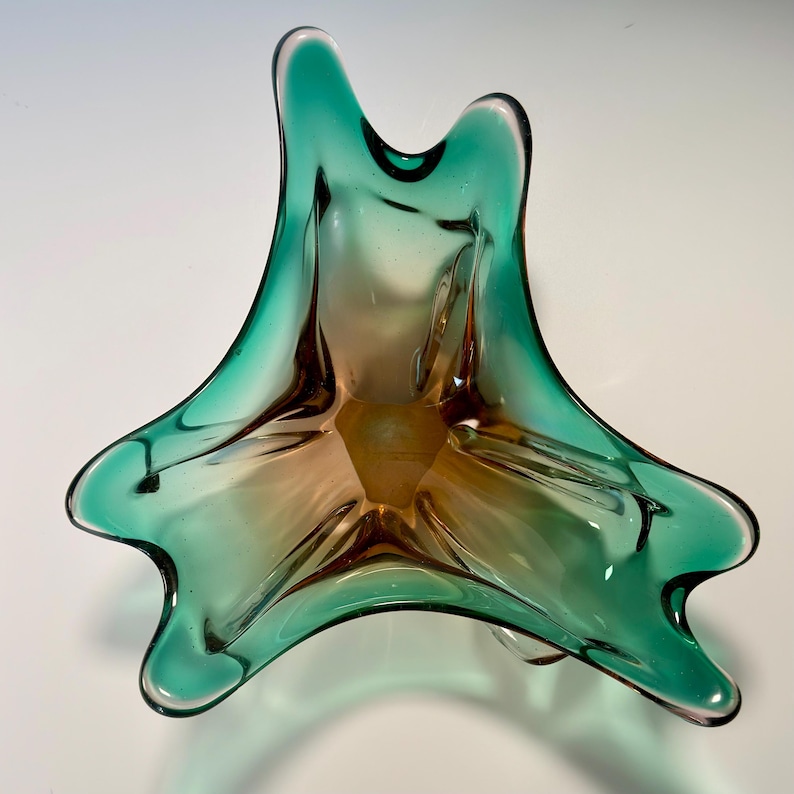 Vintage Czech art glass bowl in green and amber tones with sculptural organic shape and dramatic light reflections.