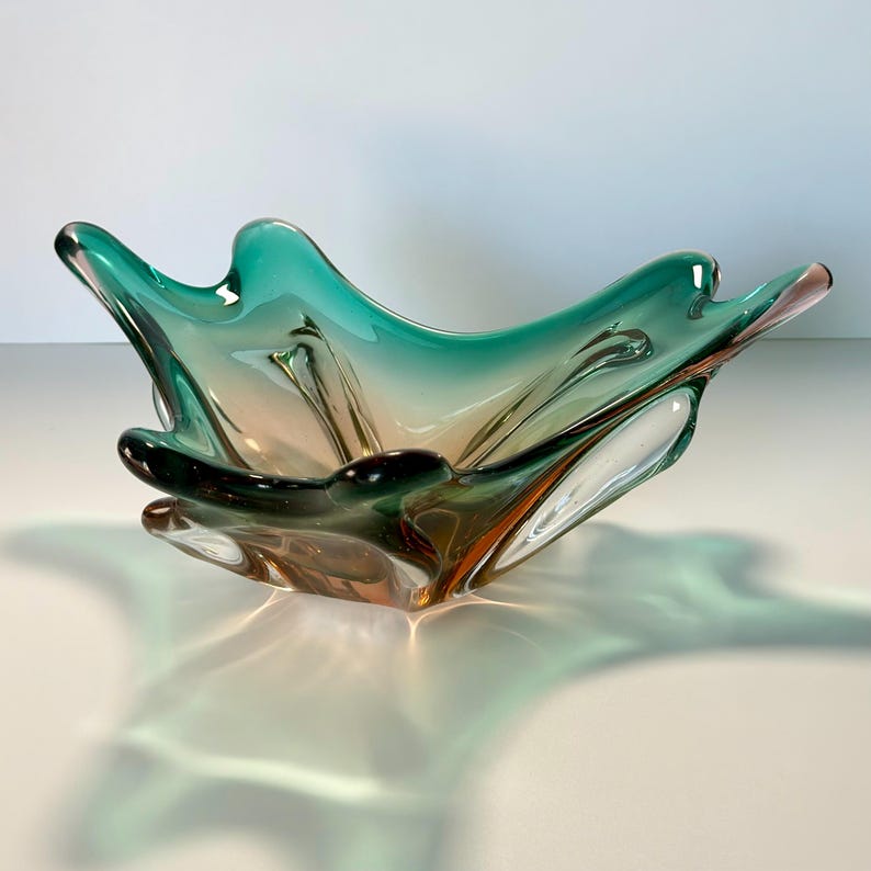Vintage Czech art glass bowl in green and amber tones with sculptural organic shape and dramatic light reflections.