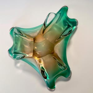 Vintage Czech art glass bowl in green and amber tones with sculptural organic shape and dramatic light reflections.