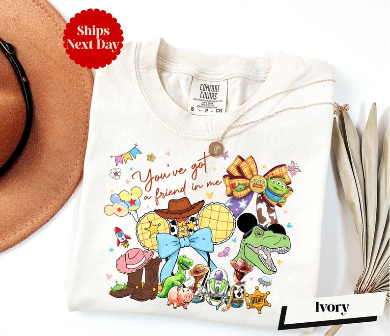 A white t-shirt with a colorful graphic design featuring characters from the Toy Story movie, including Woody, Buzz Lightyear, and other beloved characters.