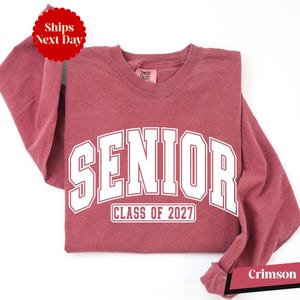 A red long-sleeved t-shirt with white text that says "SENIOR CLASS OF 2027" printed on it.