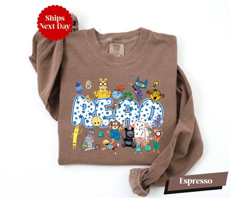 A brown t-shirt with a colorful graphic design featuring various cartoon characters and the word "READ" prominently displayed.