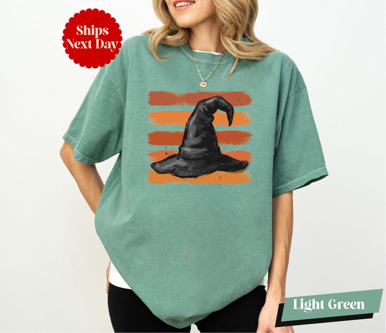 A woman wearing a green t-shirt with a graphic of a witch's hat printed on it.