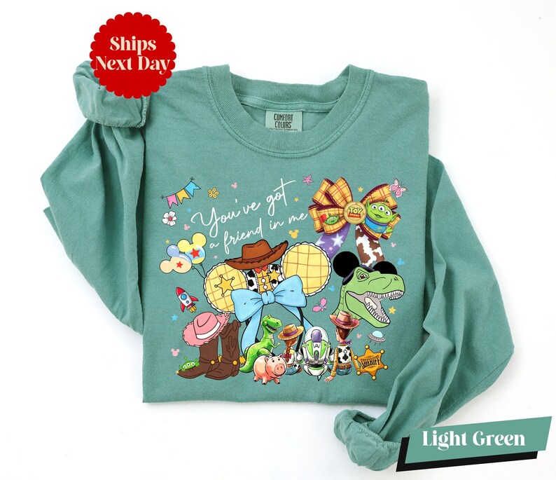 A green long-sleeved shirt with a colorful graphic design featuring various cartoon characters and a message.