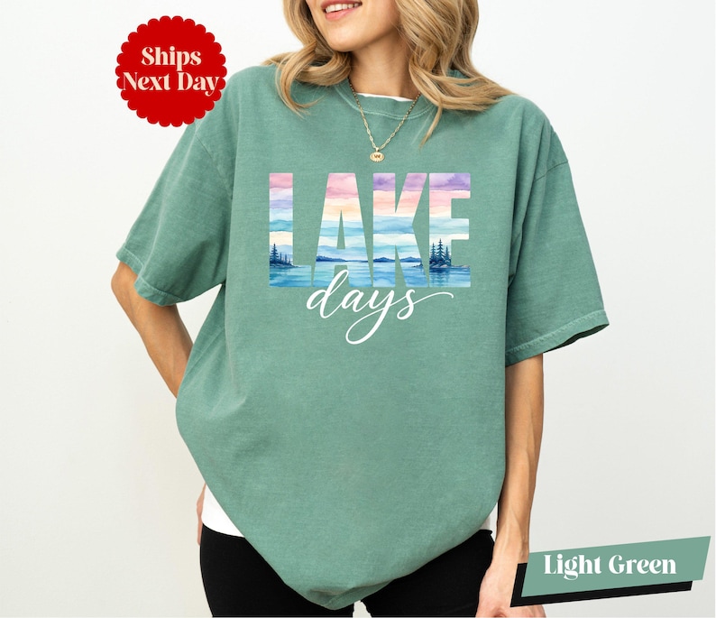 A woman wearing a green t-shirt with the word "LAKES" printed on it, standing against a white background.