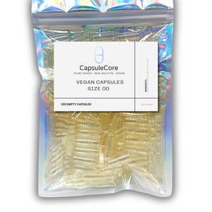 Puede incluir: Una bolsa transparente y resellable llena de cápsulas veganas transparentes. La bolsa tiene un brillo holográfico iridiscente. Una etiqueta blanca en la bolsa dice "CapsuleCore" y "VEGAN CAPSULES SIZE 00". La etiqueta también indica "200 EMPTY CAPSULES".