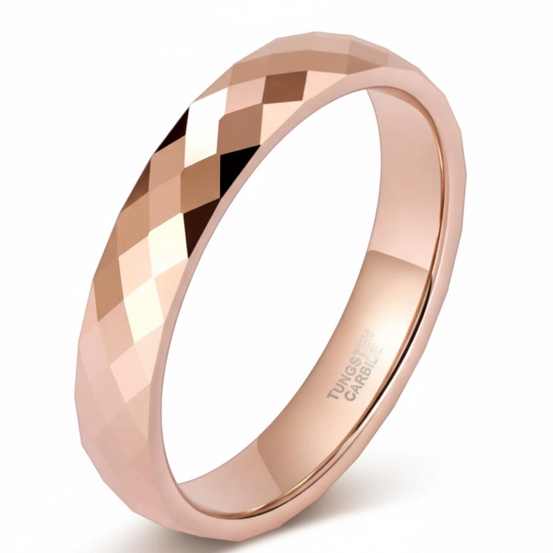 Peut inclure: Bague en carbure de tungst&egrave;ne or rose avec une surface facett&eacute;e. La bague pr&eacute;sente un motif g&eacute;om&eacute;trique avec de petits plans angulaires. L'int&eacute;rieur de la bague est lisse et poli. Le texte "TUNGSTEN CARBIDE" est visible &agrave; l'int&eacute;rieur.