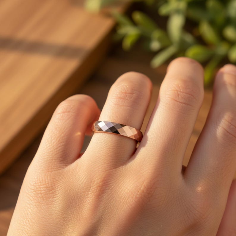 Peut inclure: Une bague en or rose avec un design g&eacute;om&eacute;trique &agrave; facettes. La bague est port&eacute;e au doigt, mettant en valeur sa surface polie et le jeu de la lumi&egrave;re sur ses facettes. Le design de la bague pr&eacute;sente une s&eacute;rie de plans inclin&eacute;s, cr&eacute;ant un effet scintillant.