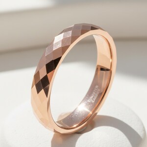 Peut inclure: Bague en carbure de tungst&egrave;ne or rose avec un design g&eacute;om&eacute;trique &agrave; facettes. La surface de la bague refl&egrave;te la lumi&egrave;re, mettant en valeur ses multiples facettes. L'int&eacute;rieur de la bague porte l'inscription "Tungsten Carbide".