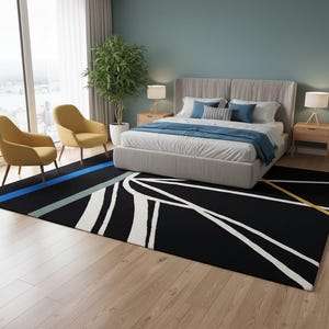 May include: A black rectangular area rug with a geometric design in white, blue, and yellow. The rug is in a bedroom with a bed, two yellow chairs, and a large window. The rug measures approximately 8 feet by 10 feet.