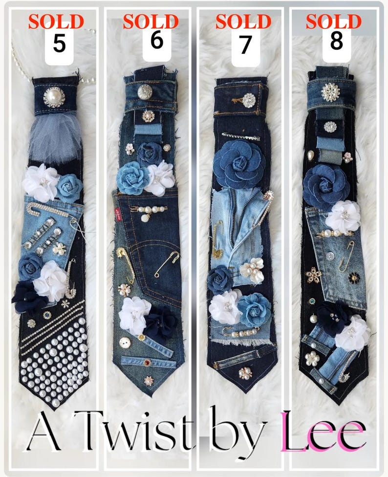 Puede incluir: Cuatro corbatas de mezclilla &uacute;nicas, cada una adornada con flores de tela, perlas y alfileres decorativos. Las corbatas son en tonos azules y negros, con el texto "A Twist by Lee" en la parte inferior. Cada corbata est&aacute; etiquetada como "SOLD" con un n&uacute;mero.