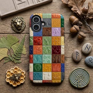 May include: A colorful phone case with a mosaic design featuring various embossed images, including a lion, deer, and hearts. The case is surrounded by natural elements like leaves, acorns, and stones, all arranged on a wooden surface.