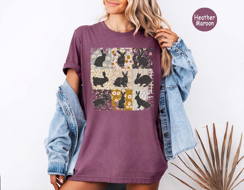 Puede incluir: Camiseta color borgo&ntilde;a con un dise&ntilde;o de patchwork con nueve cuadrados. Cada cuadrado muestra una silueta de conejo negro sobre un fondo floral o estampado. La camiseta se lleva con una chaqueta vaquera.