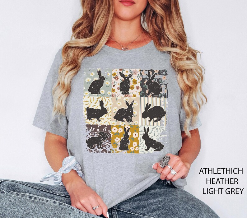 Puede incluir: Camiseta gris claro con un dise&ntilde;o de retazos de siluetas de conejos negros sobre cuadrados florales y estampados. La camiseta tiene cuello redondo y mangas cortas. El texto "ATHLETHICH HEATHER LIGHT GREY" est&aacute; impreso en el lado derecho.