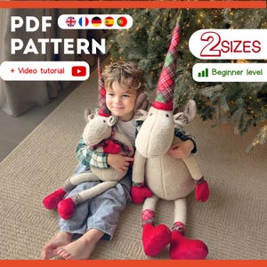 Puede incluir: Un niño sostiene dos muñecos de reno de peluche. Los muñecos tienen cuerpos color crema, detalles rojos y sombreros a cuadros. La imagen incluye el texto "PDF PATTERN" y "2 SIZES".