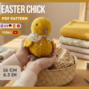 Könnte beinhalten: Ein handgemachtes gelbes Osterküken, 16 cm hoch, mit einem floralen Kragen. Das Bild enthält den Text "EASTER CHICK PDF PATTERN" und ein Videosymbol. Das Küken wird in einem geflochtenen Korb gehalten, mit Stoff und Garnrollen im Hintergrund.
