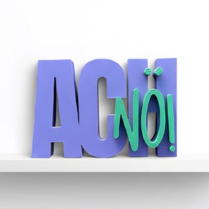Könnte beinhalten: Auf einem weißen Regal steht das Wort "ACH NO!" in 3D-Buchstaben. Die Buchstaben "ACH" sind in einem gedämpften Lila gehalten, während "NO!" türkis ist. Der Hintergrund ist weiß. Das Regal ist schlicht und modern.