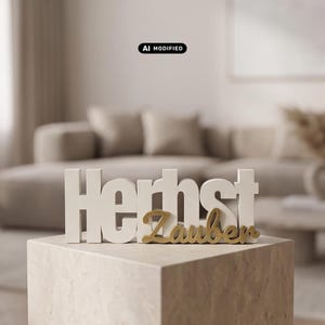 Könnte beinhalten: Ein dekoratives Tischschild mit den weißen Blockbuchstaben "Herbst" und dem davor platzierten, goldfarbenen Schreibschriftzug "Zauber". Das Objekt ist aus festem Material gefertigt und weist eine zweifarbige Gestaltung auf.