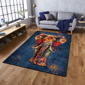 May include: A rectangular area rug featuring a colorful elephant design. The elephant is depicted with floral patterns in shades of red, orange, yellow, and blue against a dark blue background. The rug is placed on a wooden floor.