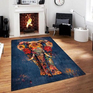 May include: A rectangular area rug featuring a colorful elephant design. The elephant is adorned with floral patterns in shades of red, orange, and yellow against a dark blue background. The rug is placed on a wooden floor.