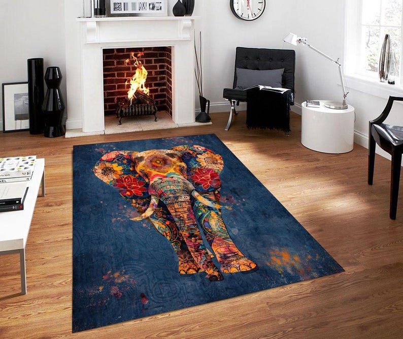 May include: A rectangular area rug featuring a colorful elephant design. The elephant is adorned with floral patterns in shades of red, orange, and yellow against a dark blue background. The rug is placed on a wooden floor.