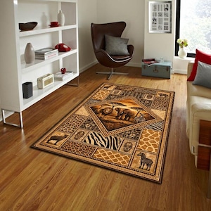 May include: Rectangular area rug with an African safari theme. The rug features a central diamond design with elephants and lions, surrounded by animal print patterns, including zebra stripes and leopard spots. The color palette includes browns, tans, and blacks.