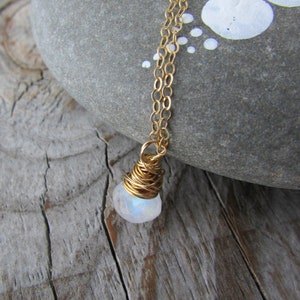 May include: A gold chain necklace with a white moonstone pendant wrapped in gold wire.